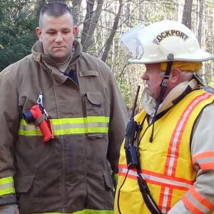 Rockport Fire Chief Bruce Woodward, in his white helmet, talks with Rockport firefighter Neal Bartley. (Photo by Lynda Clancy)