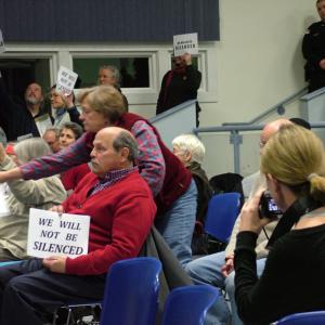 Opponents of the proposed propane terminal hold up signs in protest of the Searsport Planning Board's decision to end public comment with a dozen citizens waiting in line to speak. (Photo by Ethan Andrews)