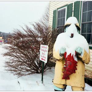 BELFAST - Behind a snow covered fisherman outside Perry's Nut House, the fisherman sign for the Jed's Restaurant is visible, at left. Both local landmark properties are currently for sale. (Photo by Ethan Andrews)