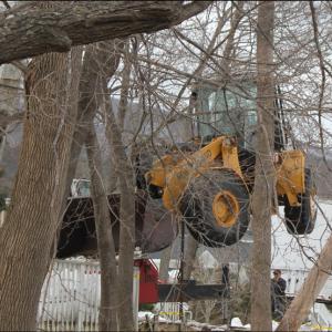 Soon after 9 a.m. on Saturday, Feb. 16, the front-end loader that had tumbled over the side of a 20-foot wall the previous day was being lifted back up from the river's edge with a crane. (Photo by Lori Van Dusen)