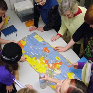 Students from the Captain Albert School in Belfast crowd around a geopolitical map of World War II after a presentation by Belfast Historical Society & Museum Director Megan Pinette, top, center. Meg Hunter, next to Pinette, recalled being a young girl in London during German air raids. (Photo by Ethan Andrews) Fourth and fifth grade students from Captain Albert School in Belfast crowd around a geopolitical map of World War II following a presentation at the school by Belfast Museum and Historical Society Director Megan Pinette, top, center. (Photo by Ethan Andrews)