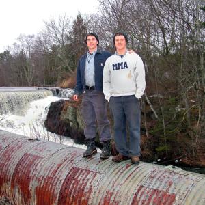 Nicholas Cabral, left, and Nicholas Berner on the penstock at Mill Dam, part of the Goose River hydroelectric generating system they recently bought and plan bring back online. (Photo by Ethan Andrews)