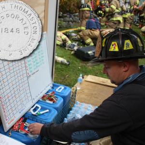 South Thomaston Fire Chief Bryan Calderwood checks the board, radio assignments and resets the safety tags to account for everybody on the fire ground at a training fire on Split Rock Road Sept. 29, 2012. (Photo by Holly S. Edwards)
