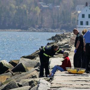 A Rockland paramedic assesses an injured woman on the Rockland Breakwater Monday afternoon while fire and EMS personnel standby to assist with moving her back to shore, where an ambulance was waiting to take her to the hospital for treatment of minor injuries, according to Asst. Fire Chief Ken Elwell. (Courtesy Rockland Fire Department/by Alan Athearn)