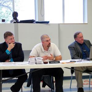RSU 20 Superintendent Brian Carpenter, left, school board chairman Anthony Bagley and Assistant Superintendent John McDonald listen to testimony opposing proposed staff and teacher cuts, May 15. The stack of envelopes on the table holds letters from students at Troy Howard Middle School supporting the school's visual art program whose sole teacher is on a list of positions to be cut next year. (Photo by Ethan Andrews)