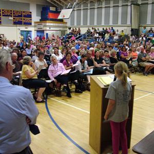 Kaitlyn Dufflemeyer, a fourth grade student at Edna Drinkwater Elementary School, addresses a crowd of 300 in the Troy Howard Middle School gymnasium during the public budget meeting for Regional School Unit 20, May 30. Dufflemeyer was among a number of people to speak in support of reinstating art positions slated to be cut in the 2013-14 budget. (Photo by Ethan Andrews)
