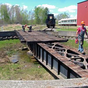 Workers dismantle the old Belfast and Moosehead Lake Railroad turntable at Unity Station, May 8. Some of the equipment is bound for the Great Smoky Mountain Railroad in North Carolina. Other pieces, including several train cars are reportedly headed to a museum in Tennessee. (Photo by Ethan Andrews)
