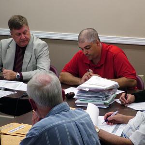 Regional School Unit 20 Board Chairman Anthony Bagley, right, tabulates weighted votes in a close decision on a change to the draft 2013-14 budget. At left, Superintendent Brian Carpenter. (Photo by Ethan Andrews)