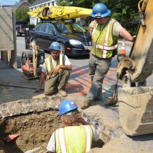 For a while, it was a real puzzle, trying to locate the pipe that led on the Mechanic Street water main. It took a few days of digging and sleuthing, and then it was shovel on metal, approximately four feet down beneath layers of tarmac, rocks and dirt. Eric Kenefick, Shaun McNulty and Lee Philbrook find the pipe using a resonator, computer coordinates and muscle power. (Photo by Lynda Clancy)