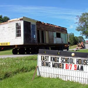 As advertised: The old East Knox School passes by the town office Wednesday morning en route to its new home at Thor-Nox Farms on Route 220. (Photo by Ethan Andrews)
