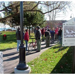 City officials placed a wreath, left, in Heritage Park to mark the moment for future generations. Along the route, Belfast historian Megan Pinette pointed out places of significance in Belfast’s past. (Photo by Ethan Andrews) 