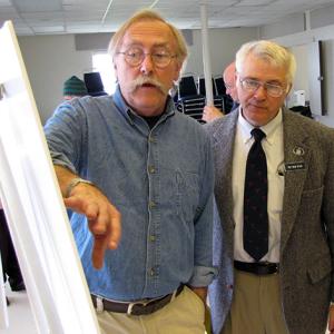 Stephen Miller, executive director of the Islesboro Islands Land Trust, left, gestures to a map of upper Penobscot Bay as Rep. Mick Devin looks on. (Photo by Tom Groening)