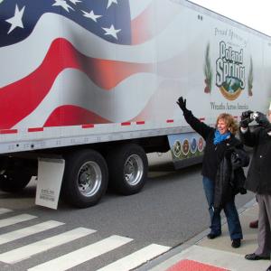 Maine First Lady Ann LePage waves to drivers from Wreaths Across America as they arrive in Belfast, Dec. 8. Next to LePage, American Legion Vice Commander Ronald Rainfrette snaps a photo. (Photo by Ethan Andrews)