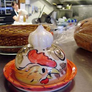 At the recently re-opened Monroe General Store, Becca Biggs tosses pizza dough for the store’s Wicked Rooster Café. In the foreground, a garlic roasting dish by local potter and store employee Bill Davis. The depiction of a rooster on the dish was coincidental, he said. (Photo by Ethan Andrews)