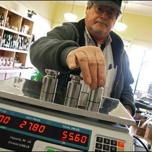 Robert Wiggin, sealer of weights and measures for 25 Midcoast municipalities, checks the accuracy of a scale at Eat More Cheese in Belfast. (Photo by Ethan Andrews)