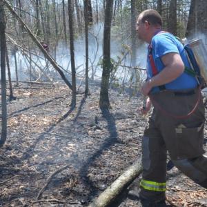 Rockport firefighter Neal Bartley works at extinguishing flames and smoldering underbrush during a woods fire May 8. (Photo by Lynda Clancy)