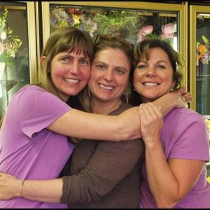 Krista Tolman, Gretchen Richards and Lisa Farley have a group hug in front of a cooler of flowers at Hoboken Gardens. (Photos by Chris Wolf)
