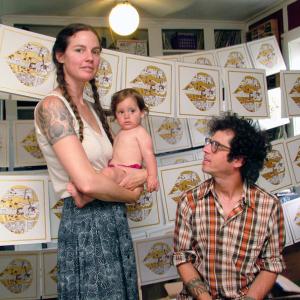 Amy Moon, Dan Beckman and their daughter Agnes at home in Belfast. The couple has been making music together for over a decade, most recently under the name Village of Spaces. Here, hand-silkscreened LP covers dry between coats in the room where much of the band’s new album, “Welcome In,” was recorded. (Photo by Ethan Andrews)