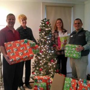 (L to R) Eric Kangas, Pam Brodis, and Rebecca Pelkey of Kangas and Associates, and Big Brothers Big Sisters CEO Alex Gaeth with the Christmas presents their employees provided for a local family.