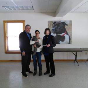 Shirley Balch (left) presents a donation check for $9,000 on behalf of the John Wilkalis Trust. Accepting the check are Executive Director Amie Hutchison, and Darlene, an adoptable cat at P.A.W.S. (Photo by Joelle Albury)