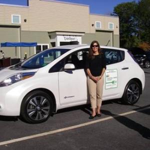 Jennifer Puser Brennan of the Greater Portland Council of Governments shows off the Nissan Leaf GPCOG leased through CMP’s PEV grant program.