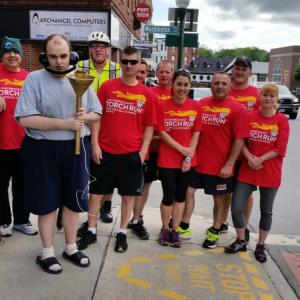 Graham Wiley, holding the torch, gathers with the runners in front of the Camden Town Office, just before he leads off the 2015 Torch Run for Special Olympics. (Photo by Sarah Shepherd)
