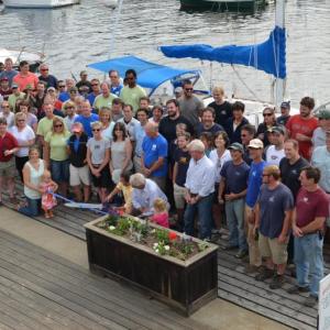 The crews of Wayfarer Marine and Lyman-Morse assemble behind the Lymans as they cut the symbolic ribbon of a new venture. (Photo by Lynda Clancy)