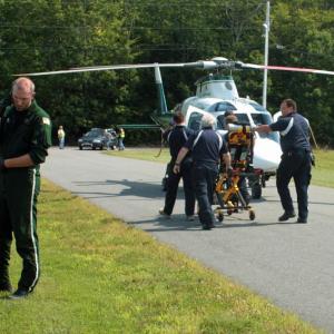 A LifeFlight of Maine crew member talks on the phone while Kergan Thomann, 29, of Lincolnville, is loaded into the helicopter to be flown to Portland for treatment of burn injuries he sustained Sunday around noon at his home. (Photo by Holly S. Edwards)
