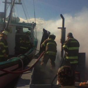 Lincolnville firefighters aboard the “Fundy Spray” douse water on the burning “Big Red.” (Photo courtesy Richie Osgood)
