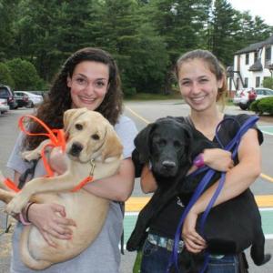 From left and in September, Nikki Viveiros, Unity College Class of 2016 and an adventure Therapy major from Somerset, Mass., and Malcolm, a then-8-month-old Labrador retriever, and Mikala Robinson, Class of 2015 and a conservation law enforcement major from Danvers, Mass., with Malcom’s brother, Mac. (Courtesy Facebook/Guiding Eyes for the Blind at Unity College)