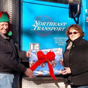 Truck driving Santa, Terry Gray, brings free gifts from the Bruce Roberts Toy Fund of Portland to Becky Ruggieri of Warren Congregational Church. (Photo Courtesy of Jeff Payson)