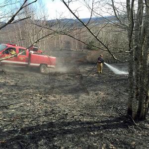 Hope firefighters use portable water tanks to contain and extinguish a woods fire on Sexton Avenue Sunday afternoon. (Courtesy Justin Ford)