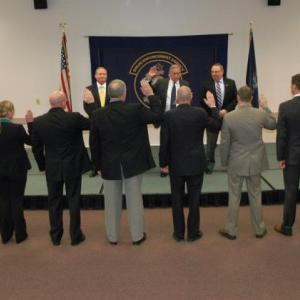 With Governor LePage and MDEA Director Roy McKinney looking on, Public Safety Commissioner John Morris administers the oath of office to thirteen new state drug agents.