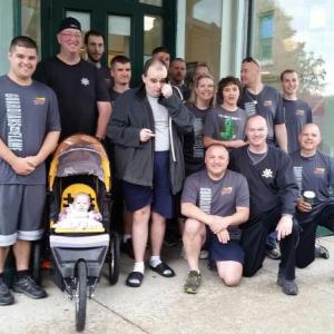Graham Wiley (right of stroller), a Special Olympics athlete, gathers with the runners before they take to the streets for the annual Law Enforcement Torch Run. (Photo by Sarah Shepherd)