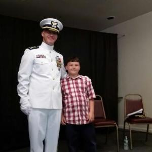Michael Bollinger, the new commanding officer of the U.S. Coast Guard Cutter, Abbie Burgess, stands on stage with his son Daniel following the Change of Command Ceremony at the Rockland Elks Lodge. (Photo by Sarah Shepherd)