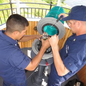 U.S. Coast Guard petty officers MK3 Joseph Pineda and BMC Sean Dolan work on replacing the lampchanger in the light at Curtis Island on July 18. (Photo by Bob Trapani)