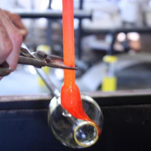 Colored molten glass is carefully guided around and attached to the “lip rim” of a drinking glass before it is cut with a pair of steel shears, at Jacobson Glass Gallery in Montville. (Photo by Holly S. Edwards)