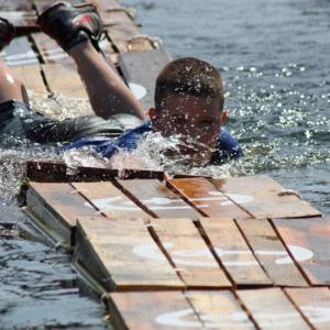 Unwilling to give up, this young man worked hard to make his way across the crates in Camden Harbor Saturday, as the crowd enthusiastically cheered him on. (Photo by Holly S. Edwards)