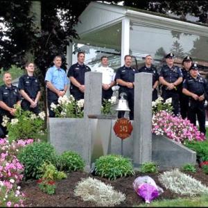 Members of the Rockland Fire and Police departments line up behind the 9/11 Memorial that sits at the corner of the fire station lot. (Photo by Sarah Thompson)