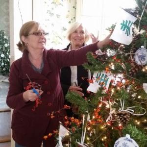 Mary Kay Felton and Susan Freeman, of the Lady Knox Chapter of Daughters of the American Revolution, decorate a holiday tree in the dining room featuring miniature ornaments that are replicas of the china used by General Henry and Lucy Knox. (Photo by Sarah Shepherd)
