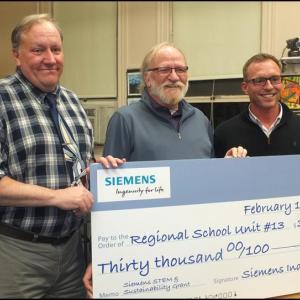 RSU 13 Superintendent John McDonald, Board Chair Steve Roberts and Tom Seekins of Siemens Industry Inc. Seekins is presenting a check for $30,000 to the RSU 13 school system. (Photos by Chris Wolf)