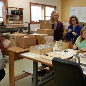 A member of the Pieceworks, Inc., team, Nikki Gates, demonstrates the production process for Betty Gensel of the Women’s Business Center, Amy Bassett of the SBA’s Maine District Office, and Cathy Roberts owner of Pieceworks, Inc.