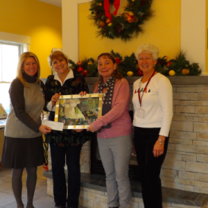 Susan Baines, proprietor of the Kelpie Gallery presents a piece of Erik Lundin's artwork and a check to benefit the Sussman House. Pictured are (left to right) Ellie Willmann, PBMC Foundation; Susan Baines, Kelpie Gallery; Heidi McCaffery, MeHealth Care at Home; and Judy Hengerer, Sussman House Volunteer.