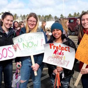 Annika Charland, Lillian Dailey, Ella Tassoni and Anikka Reinwang display their placards during Thursday’s walkout.