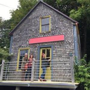 Morgan Rowe, far left, Maggie McGaw, and Marty Rowe stand on the porch of 56 Main St. on the day that they acquired the keys to the building in August, 2017. (Photo courtesy of Morgan Rowe)