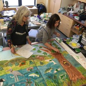 Randy Fein helps a Lincolnville student Marlie Berard wit painting her relief owl. (Photo courtesy Randy Fein)