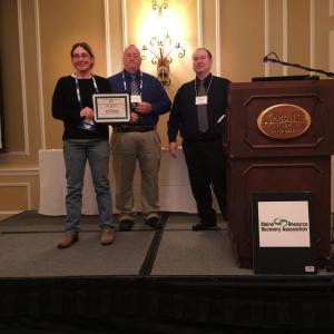 Eva Murray, Recycling and Solid Waste Coordinator for Matinicus Island, displays her award for 2018 Maine Recycling and Solid Waste Manager of the Year as MRRA President Ross Nason and Executive Director Victor Horton look on. (Photo courtesy Maine Resource Recovery Association)