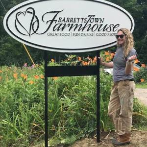 Jessi Wootton stands beside the sign welcoming guests to her restaurant, Barrettstown Farmhouse, located at 42 Hatchet Mountain Road in Hope. Barrettstown Farmhouse will open for business on Wednesday, August 1. (Photo courtesy of Jessi Wootton)