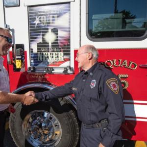 Rockport Fire Chief Jason Peasley and firefighter Charlie Knight exchange a hearty handshake following the dedication of the new “Squad 25” firetruck July 19. (Photo by Peter Ralston)