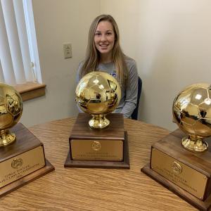 Kassie Krul with the three state championship trophies the Camden Hills girls soccer has won over the past three seasons. (Courtesy Steve Alex)